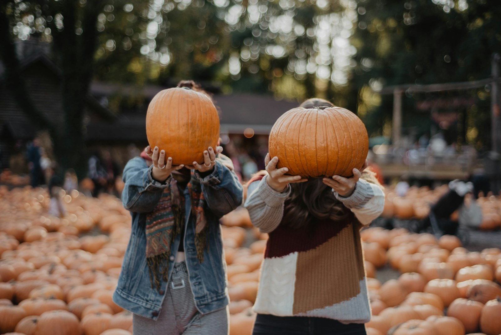 Parent carrying a baby in an orange knit cap at a fall pumpkin patch